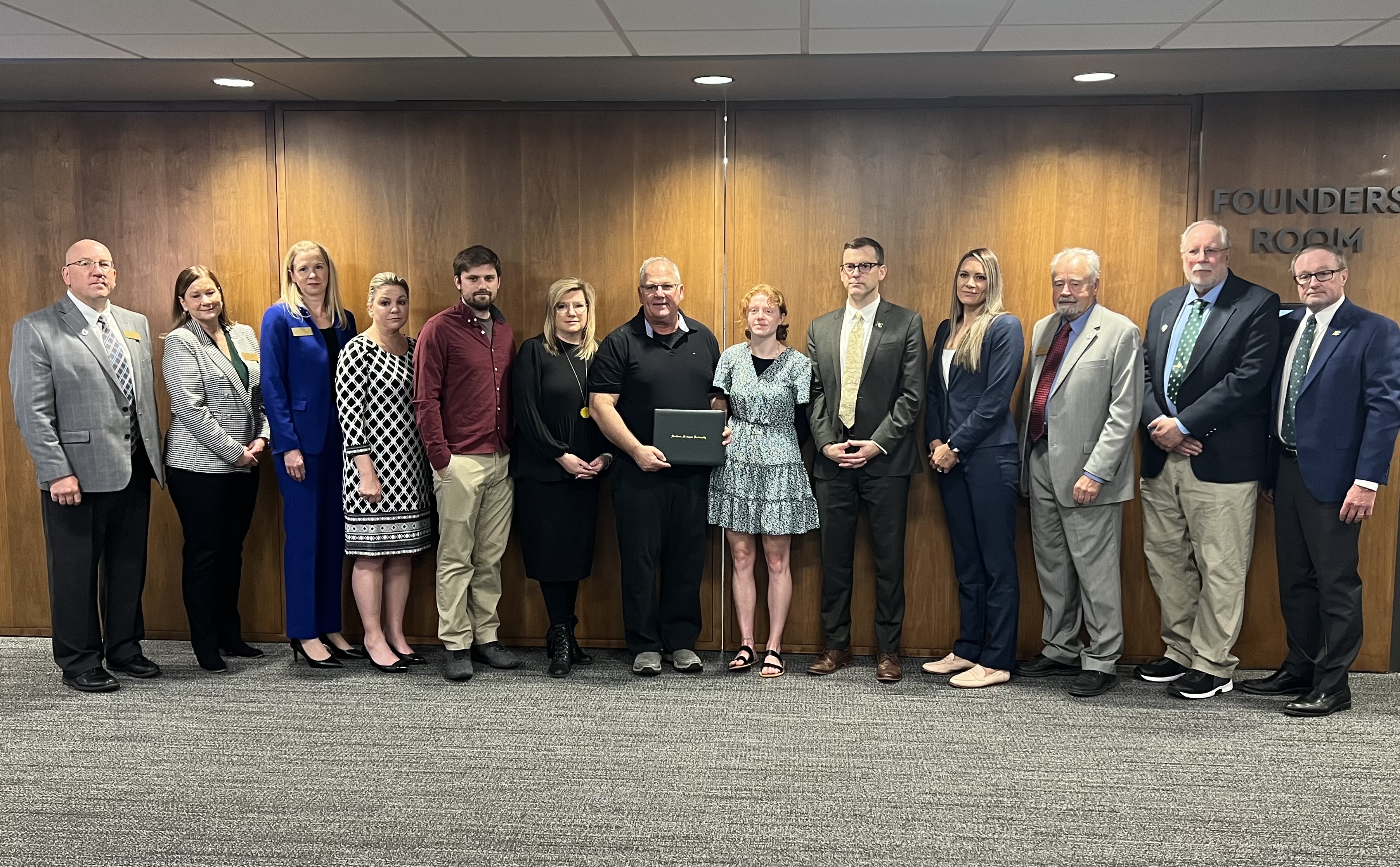 NMU trustees and President Brock Tessman surround the Needham family after the presentation.