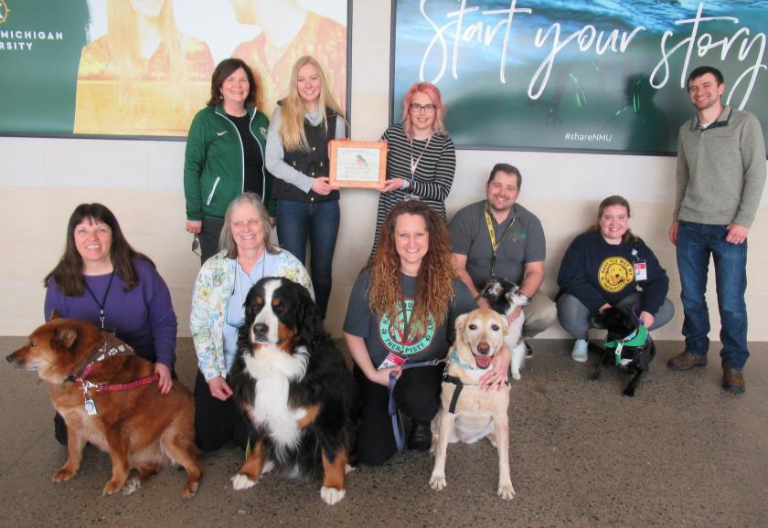 Pictured are: (front row from left) Pet Partners Ann Dausey, Kelly December and Tanya Savage with their dogs; and (back row from left) health fair committee member Sharon Carey, Health Promotion Society President Haley Anderson, Pet Partner Kim Benson-Custard (holding the award), Rick Custard, Bethany Rudness, and health fair committee member Matt Kilgas. 