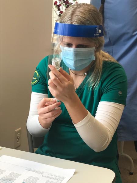 A nursing student prepares to administer a vaccine.