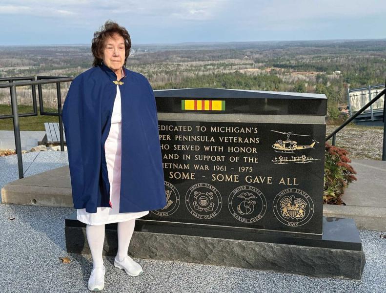 Stolze stands at the Vietnam War Memorial on top of Pine Mountain. She is dressed in the Upper Peninsula Nurses Honor Guard’s traditional white uniform, cap, and blue and red cape. (Terri Castelaz/Daily News photo)