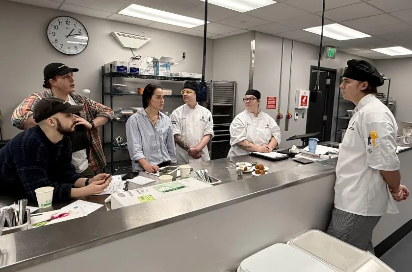 Adam Cunningham presents his Onigiri Arancini bites to the judging panel (from left): NMU alumni Orion Ingmire, Nate Brodeur and Kelsey Weeder from the Delft, Teaching Assistant Danny Prudhomm and Assistant Professor Alden MacDonald.