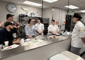 Adam Cunningham presents his Onigiri Arancini bites to the judging panel (from left): NMU alumni Orion Ingmire, Nate Brodeur and Kelsey Weeder from the Delft, Teaching Assistant Danny Prudhomm and Assistant Professor Alden MacDonald.