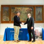 FinnU President Philip Johnson (left) and NMU President Fritz Erickson shake hands