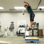 A student jumping and landing on the flooring sample.