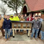 Northern Michigan Constructors surround the free library they built and installed.